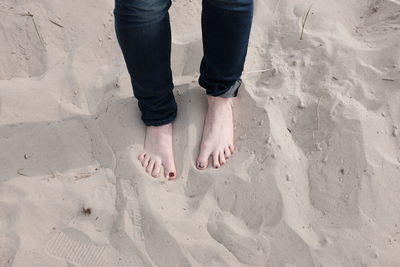 Low section of woman standing on sand at beach