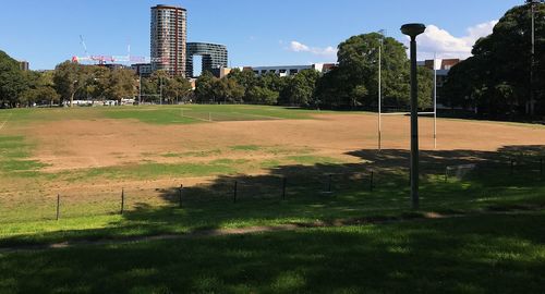 Scenic view of field by buildings against sky