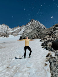 Full length of woman standing on snowcapped mountain against sky