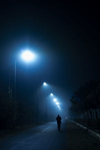 Rear view of man walking on street at night