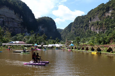 People on boat in river against mountains
