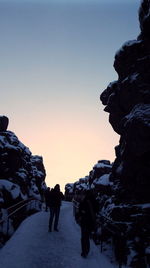People on snow covered landscape against clear sky