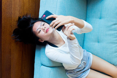 Asian teenage girl lay down using mobile phone