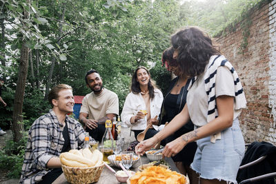 Young male and female friends talking to each other at garden party in back yard