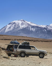 Off-road vehicles parked against clear blue sky during sunny day