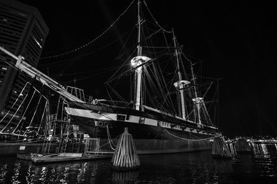 Illuminated boats moored at harbor against sky at night