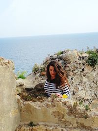 Young woman by sea against sky