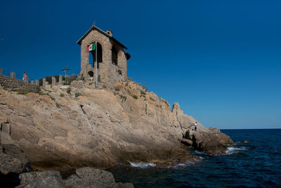 View of rock by sea against clear sky