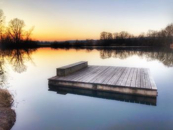 Pier on lake against sky during sunset