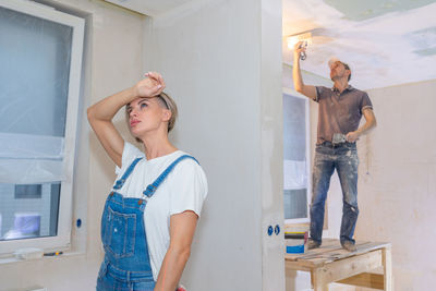 Side view of young woman standing against wall