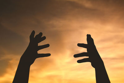 Low angle view of silhouette hand against sky during sunset