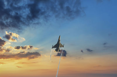 Low angle view of airplane flying against sky during sunset