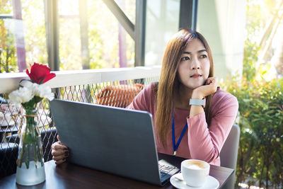 Young woman using phone while sitting on table