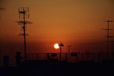 Silhouette street lights against orange sky