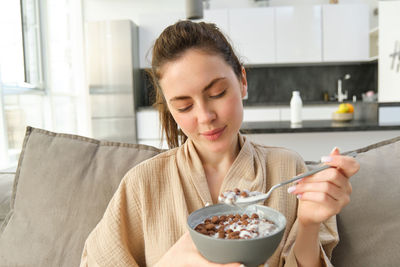 Portrait of young woman having food at home