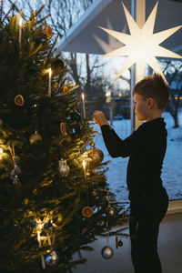 Boy decorating christmas tree at home