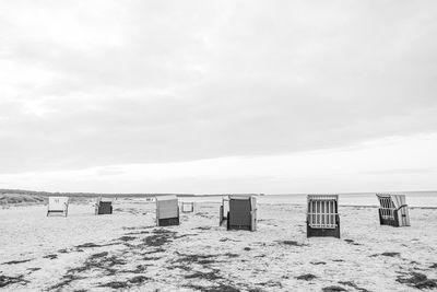 Hooded chairs on beach against sky