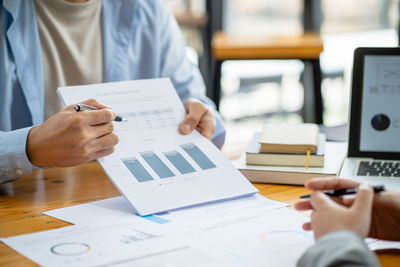 Midsection of business people working on table