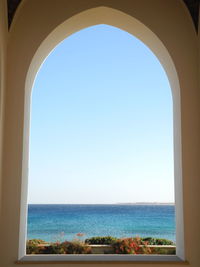 Scenic view of sea against clear blue sky seen through window