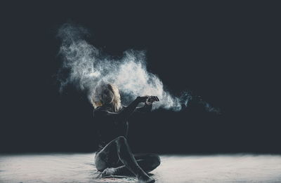 Creative portrait of young woman against black background