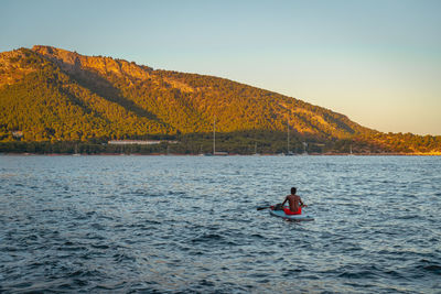 Man on boat in lake against clear sky