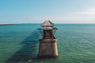 Lighthouse by sea against sky