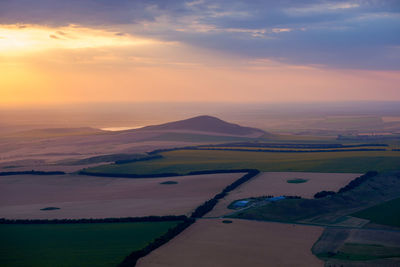 Scenic view of agricultural field against sky during sunset