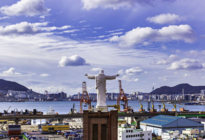 Statue in city against cloudy sky