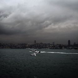 Boats in sea against cloudy sky