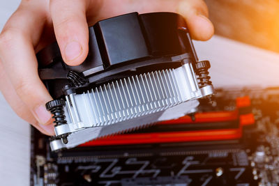 Close-up of cropped hand holding circuit board fan on table