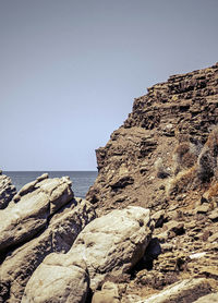 Rock formations by sea against clear sky