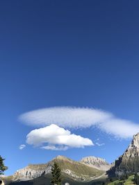 Low angle view of snowcapped mountains against blue sky