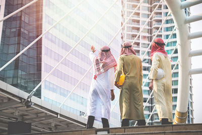 Architects in dish dash standing against modern buildings in city