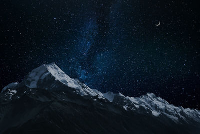 Scenic view of snowcapped mountains against sky at night