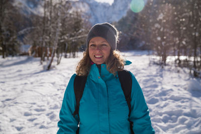 Portrait of smiling woman standing on snow covered land
