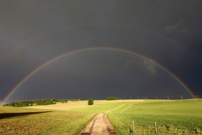 Scenic view of field against rainbow in sky