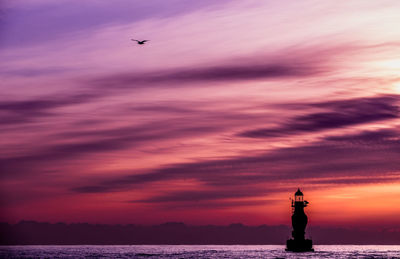 Silhouette of statue against cloudy sky during sunset