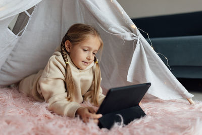 Young woman using mobile phone while sitting on bed at home