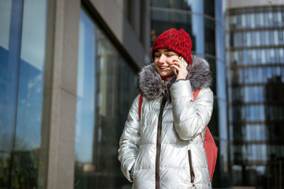 Young woman in a winter jacket with a phone in hand