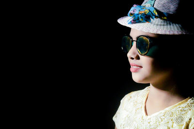 Portrait of little model wearing sunglasses against black background