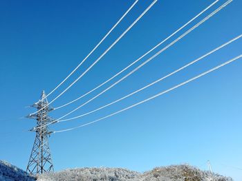 Low angle view of electricity pylon against blue sky