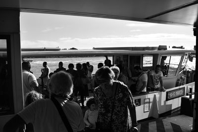 People standing by sea in city against sky