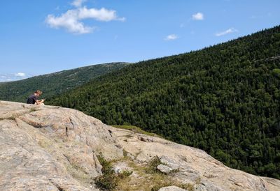 Man standing on rock against sky