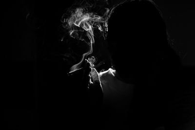 Man smoking cigarette against black background