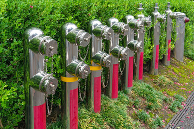 Row of metal fire hydrant boosters with green hedge on the background