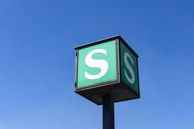 Low angle view of road sign against clear blue sky