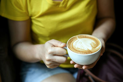 Midsection of coffee cup on table at cafe