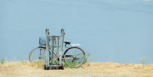 Abandoned bicycle on field against wall