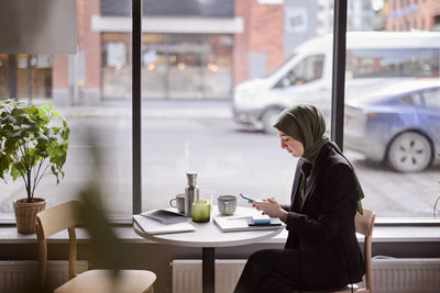 Woman using cell phone in cafe