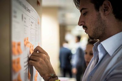 Side view of man sticking adhesive notes on board